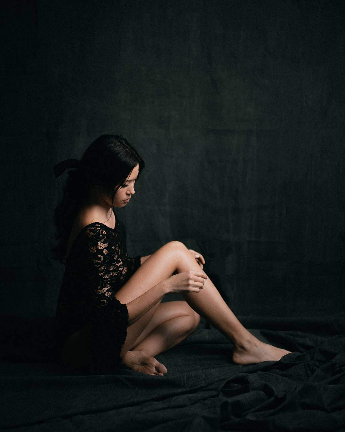 charleston studio boudoir portrait dark backdrop with soft window light and girl in black lace bodysuit
