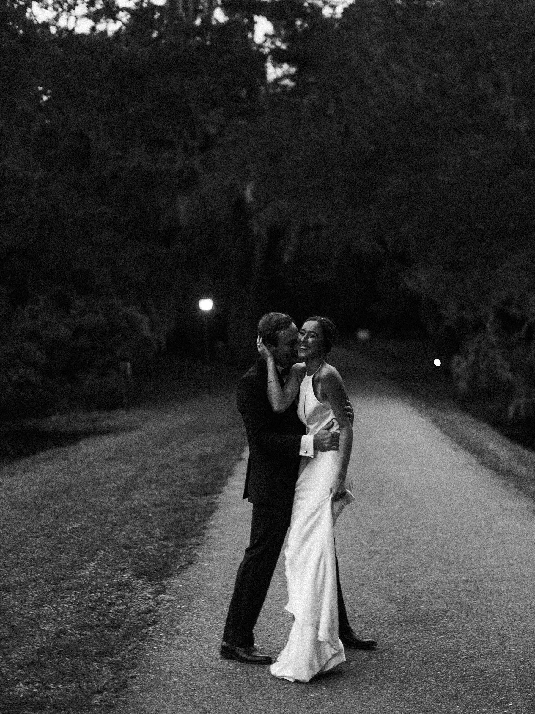 charleston sc wedding couple in black and white at legare waring house wedding with bride laughing while dancing