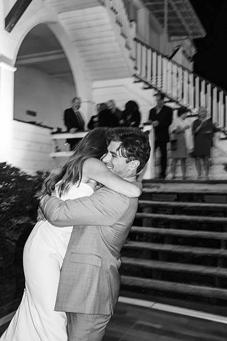 black and white wedding photo of bride and groom dancing under string lights at pelican inn pawley's island