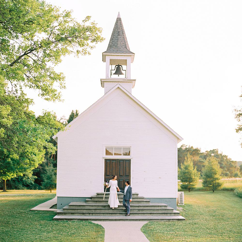 bride and groom in front of church ceremony location at felt mansion best michigan wedding venue by brian d smith photography