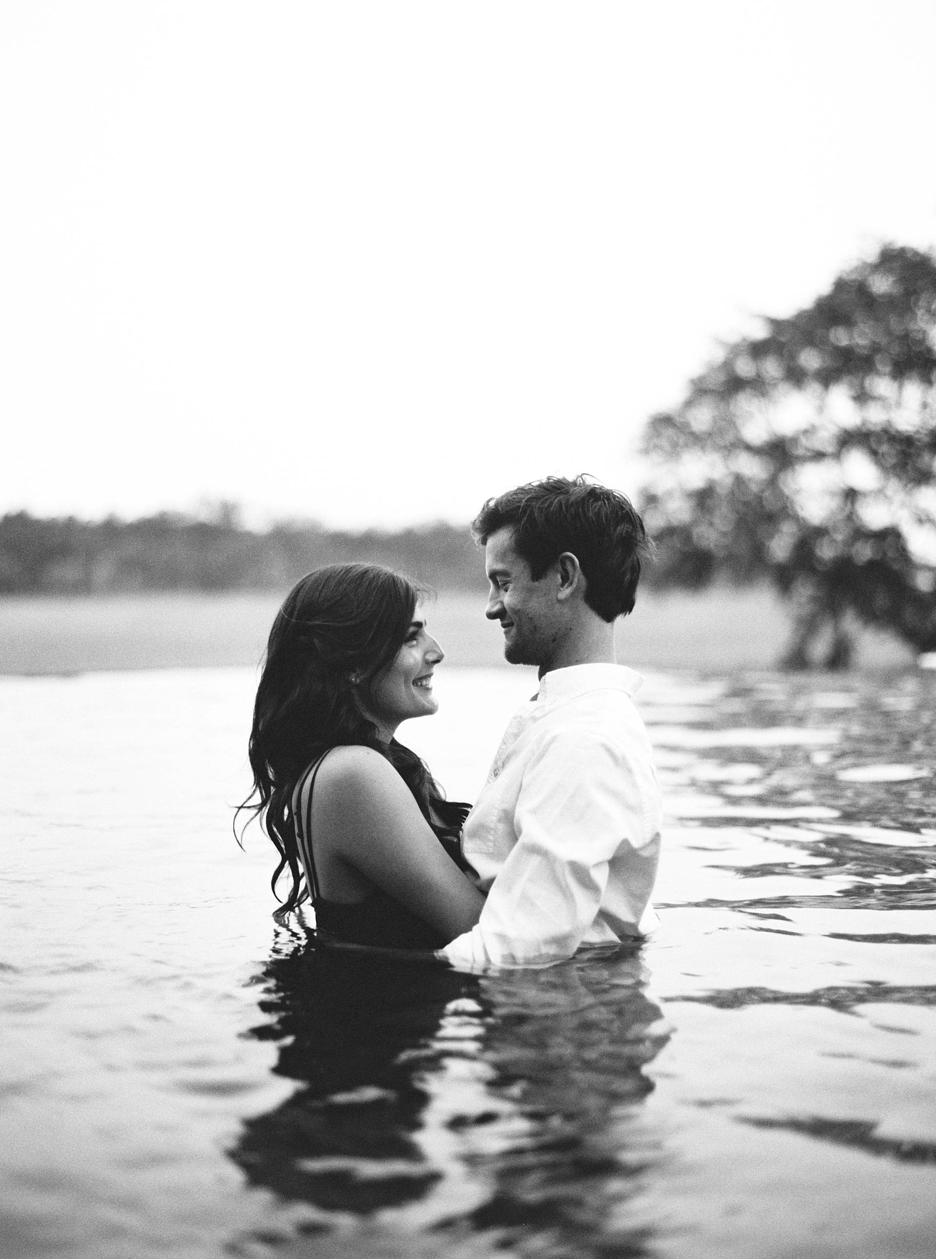 bride and groom in pool for destination wedding charleston engagement photos on black and white film