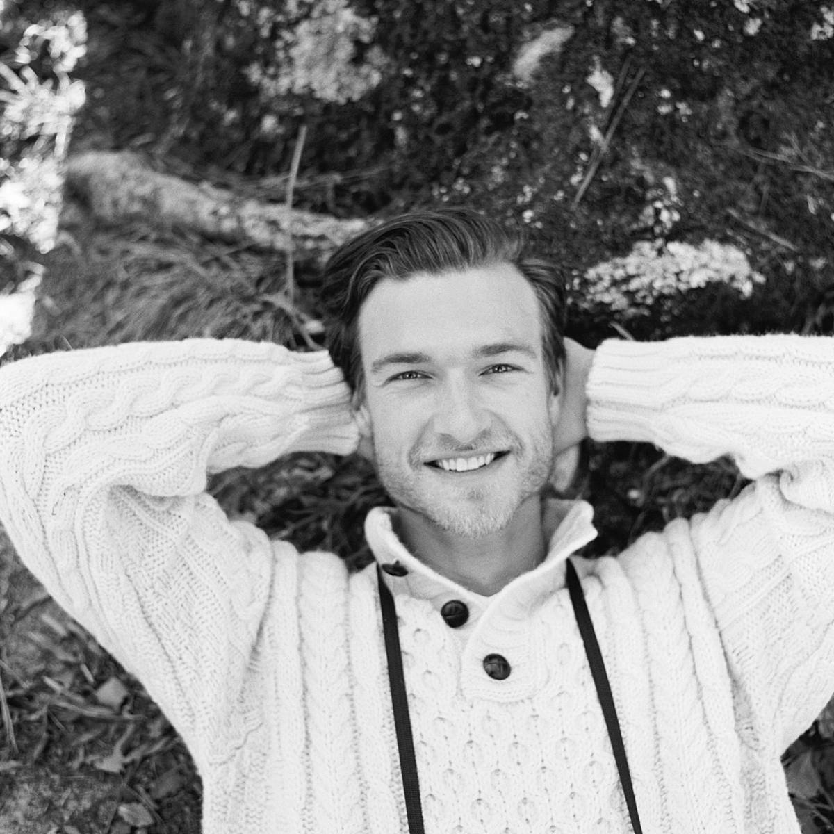 groom leaning against tree during destination micro wedding on black and white film near charleston south carolina at wavering place