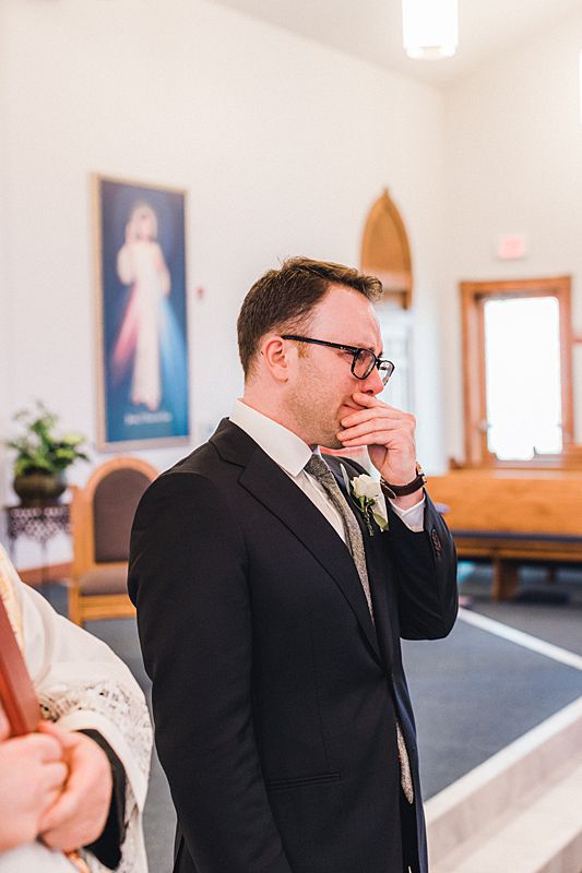 groom crying at alter during catholic wedding ceremony in Northern Michigan